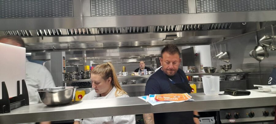 A chef and delegate checking food preparation in a commercial kitchen