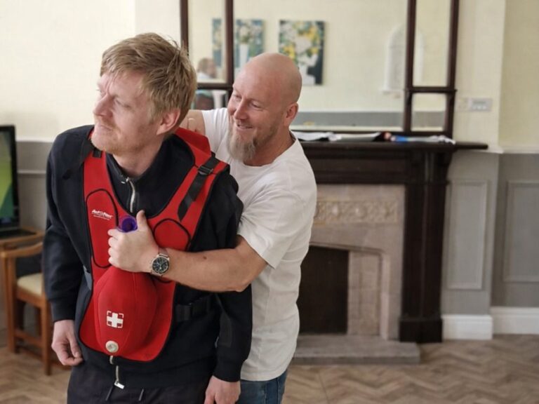 A trainer demonstrating choking first aid on a delegate wearing a choking training vest