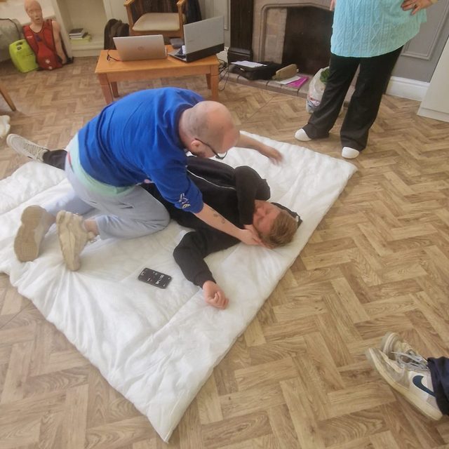 Placing a casualty in the recovery position during first aid training