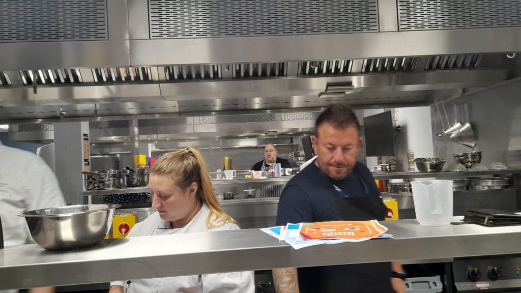 A chef and delegate checking food preparation in a commercial kitchen