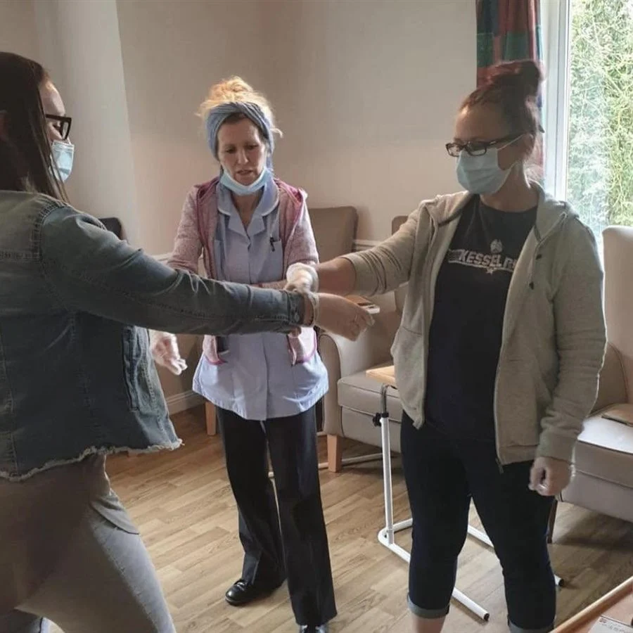 Delegates practising a breakaway from a two-handed grab in a care home lounge