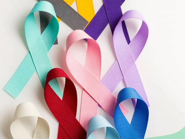 Cancer awareness ribbons in many colours laid on a white background