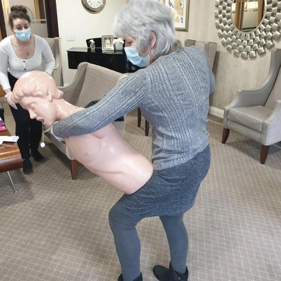 A delegate practising choking first aid on a choking manikin while a colleague watches