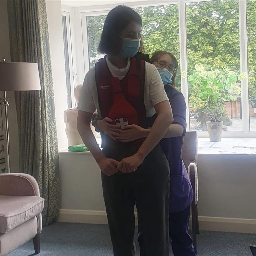 A trainer demonstrating abdominal thrusts on a delegate wearing a choking training vest
