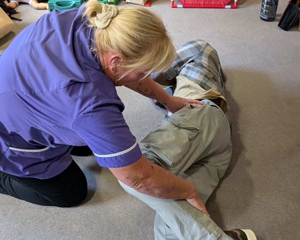 A care worker rolling a delegate into the recovery position during first aid training