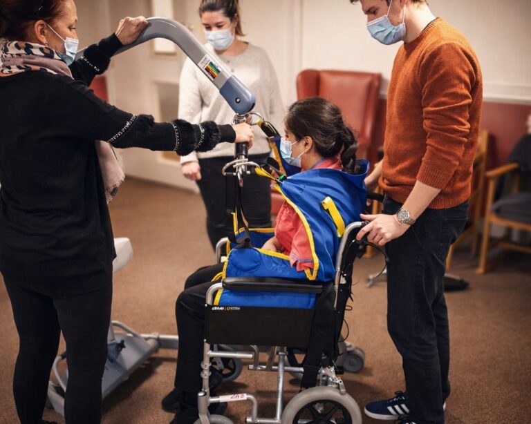 Delegates practising using a hoist with a person in a wheelchair during moving and handling training