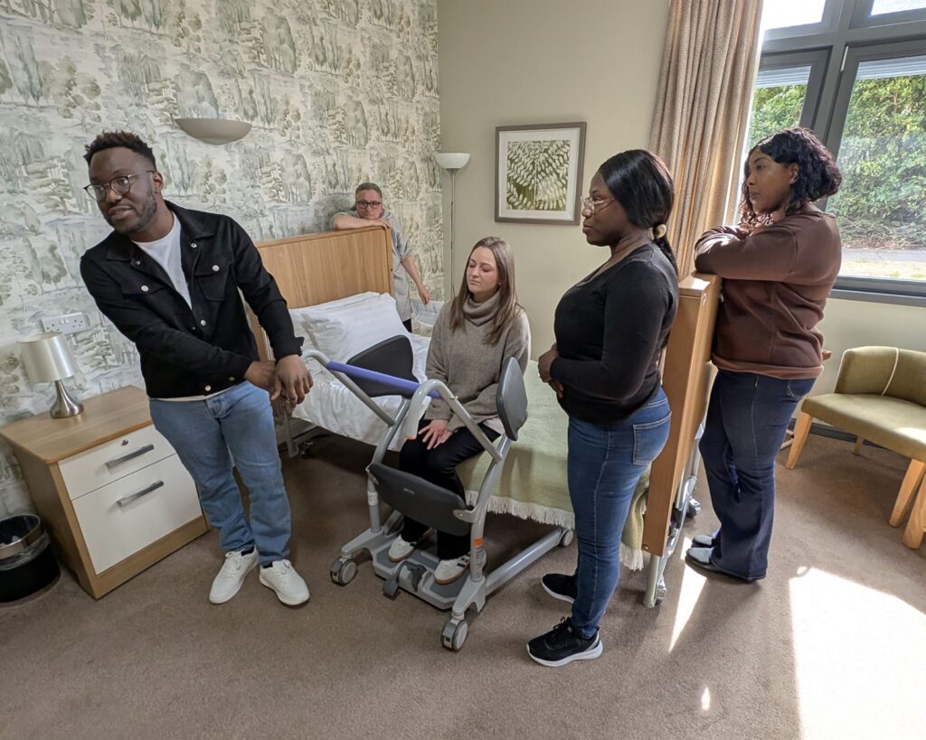 Delegates watching a moving and handling demonstration with a stand aid during a training session