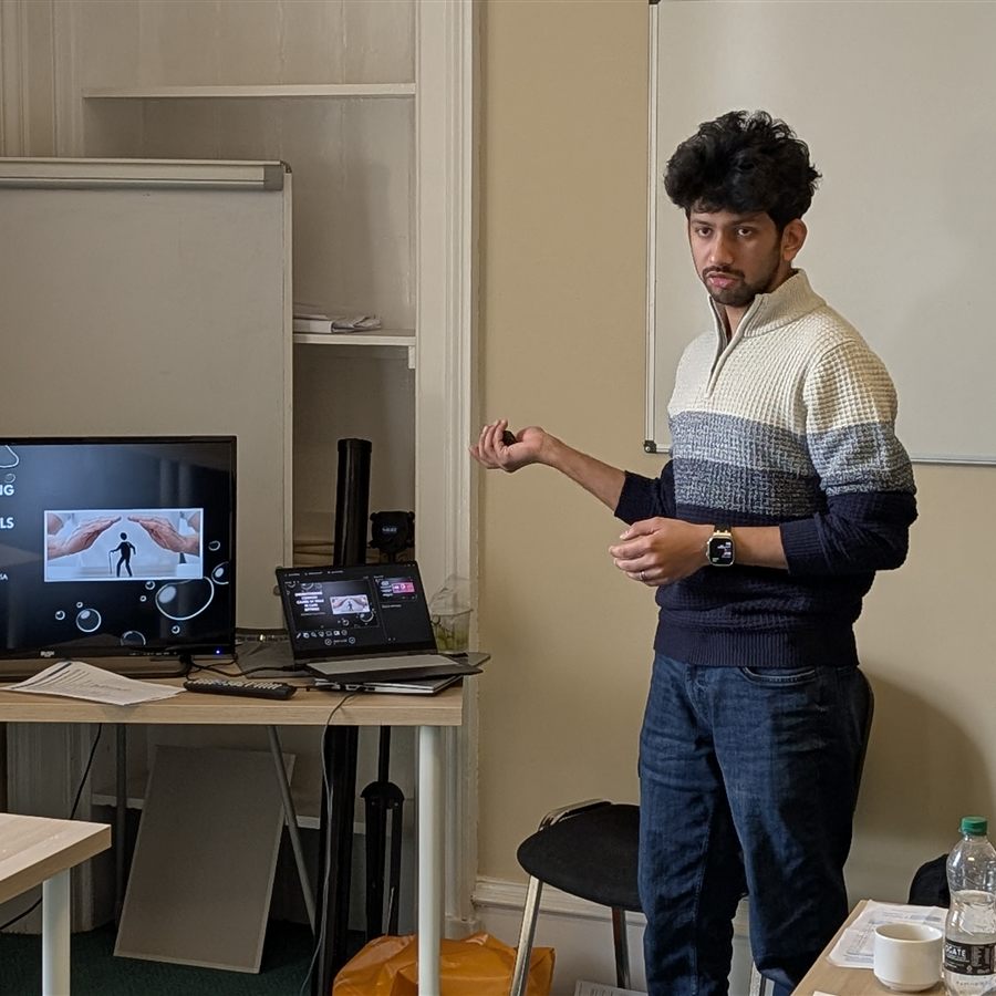 A trainee trainer presenting to the group beside a slide on screen during Train the Trainer